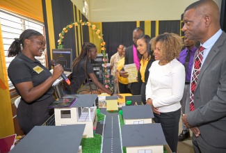 Minister of Education, Skills, Youth and Information, Senator Dr. the Hon. Dana Morris Dixon (second right), listens while first-year Mathematics student, at The Mico University College, Dorrianne Bennett (left), makes a point, during the University’s recent Mathematics Expo 2026, held at the institution. Pictured at right is President of the University, Dr. Asburn Pinnock.
