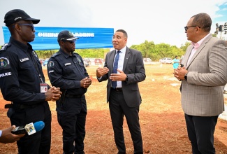 Prime Minister, Dr. the Most Hon. Andrew Holness (second right), in discussion with Commanding Officer for the St. Catherine North Division, Senior Superintendent of Police (SSP) Hopeton Nicholson (second left), while Commander of Zone 4 in the Police Division, Deputy Superintendent of Police (DSP) Fitz-Albert Linton (left), and Member of Parliament for St. Catherine West Central, Dr. the Hon. Christopher Tufton, look on. Occasion was the handover of 34 serviced lots at the Cherry Gardens Housing Development in Kitson Town to contributors of the National Housing Trust (NHT), on April 15.
