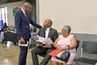 State Minister in the Ministry of Industry, Investment and Commerce, Hon. Delano Seiveright (seated centre), converses with President of the East Jamaica Conference (EJC) of Seventh-day Adventists, Dr. Meric Walker (standing left), during the church