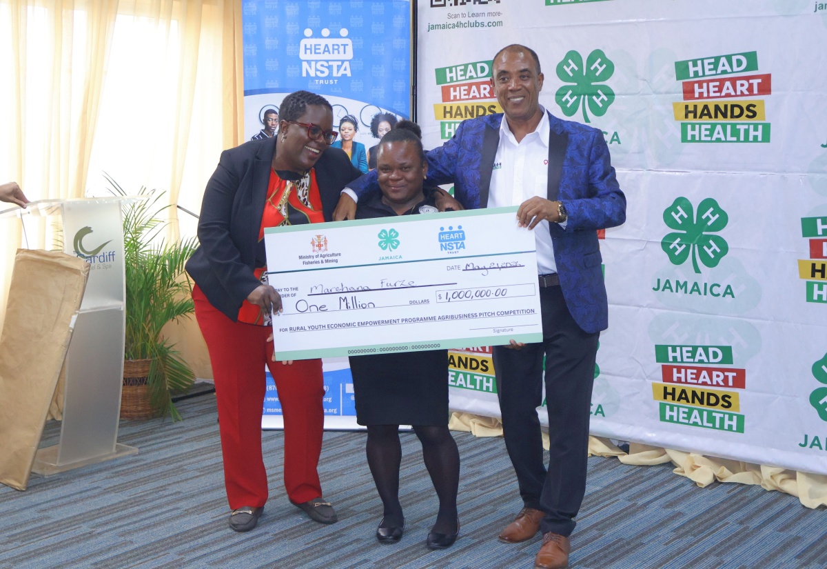 Executive Director of the Jamaica 4-H Clubs, Peter Thompson (right) and ​​Manager of Entrepreneurial Skills Development at the HEART NSTA/Trust, Stacy Mignott, present the first place prize of $1 million in the Rural Youth Economic Empowerment Programme (RYEEP) National Agribusiness Pitch Competition, to Marshana Furze from Westmoreland. Occasion was the finals of the competition held at the Cardiff Hotel in Runaway Bay, St. Ann on Thursday, May 21.