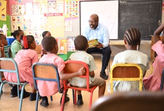 Senior General Manager for Corporate Services at the National Housing Trust (NHT), Neil Miller, shares a story with students at the Amy Bailey Basic School in Kingston, on Read Across Jamaica Day, which was observed on Tuesday (May 5).