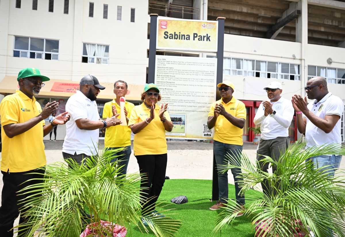 Minister of Culture, Gender, Entertainment and Sport, Hon. Olivia Grange (centre), applauds after unveiling a newly designed storyboard illustrating the history of Sabina Park as part of the National Labour Day Project being undertaken at the site. Joining her (from left) are Permanent Secretary in the Ministry, Denzil Thorpe; Executive Director of the Jamaica National Heritage Trust (JNHT), Dr. Leslie Harrow; President of the Jamaica Cricket Association (JCA), Dr. Donovan Bennett; Minister of Labour and Social Security, Hon. Pearnel Charles Jr.; Chief Executive Officer of the Kingston and St. Andrew Municipal Corporation (KSAMC), Robert Hill; and former Jamaican cricketer, Nehemiah Perry.
