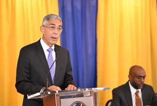 Governor of the Bank of Jamaica (BOJ), Richard Byles, addresses the Quarterly Monetary Policy Press Conference at the Garden Hotel in Mandeville, Manchester, on Tuesday (May 26). Seated at right is Senior Deputy Governor, Dr. Wayne Robinson.

