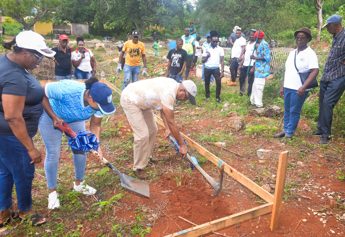 Chairman of the St. Catherine Municipal Corporation and Mayor of Spanish Town,  Councillor Norman Scott (right), along with Parish Manager at the Social Development Commission (SDC), Shana-Lee Archibald (centre), break ground for the construction  of  sanitary facilities at the Barry and Lloyd Cemetery in Kitson Town, St. Catherine on Monday (May 25). Looking on at left is Chief Executive Officer (CEO) of the St. Catherine Municipal Corporation, Marvalyn Pitter. The cemetery was the St. Catherine Parish Project for Labour Day 2026. 