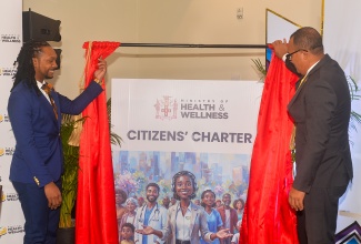 Minister of Health and Wellness, Dr. the Hon. Christopher Tufton (right), officially unveils the Ministry’s Citizens’ Charter and Wait Experience Programme, during a ceremony held on May 13, at the Courtyard by Marriott Hotel in New Kingston. At left is Principal Director at the Ministry, Dr. Kimorley Humphrey.
