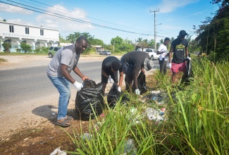 Head of the Lauriston and Thompson Pen 4-H Club, Shian Christie (left), and club members remove garbage from a section of the Sligoville Main Road in St. Catherine, during Labour Day 2026 activities on May 25.