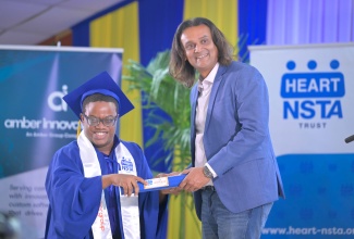 Founder and Chief Executive Officer of the Amber Group, Ambassador Dushyant Savadia (right), presents graduate Javaughn Douglas with his certificate of completion during the recent Amber HEART Academy Graduation Ceremony for the Class of 2026.

