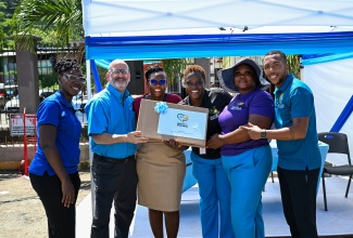 Pan American Health Organization (PAHO)/World Health Organization (WHO) representative to Jamaica, Bermuda and the Cayman Islands, Ian Stein (second left); and Acting Director, Family Health Unit in the Ministry of Health & Wellness, Julia Rowe-Porter (left), present the Port Maria Health District with their prize for winning the HPV jingle competition during a Vaccination Drive and Health Fair in Port Maria, St. Mary, on April 30.