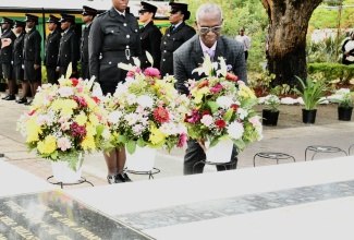 Minister of Local Government and Community Development, Hon. Desmond McKenzie, places a floral tribute at the Eventide Home Monument at National Heroes Circle on Wednesday (May 20) during the National Day of Remembrance for the victims of the Eventide Home Fire.