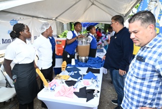 Minister of Water, Environment and Climate Change, Hon. Matthew Samuda (right), and Custos Rotulorum of St. Ann, Joseph Issa (second right), interact with students from the HEART College of Hospitality Services during the Northeast St. Ann Health and Job Skills Fair held at Lawrence Park in St. Ann’s Bay on May 8.