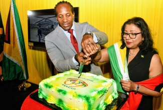 State Minister in the Ministry of Foreign Affairs and Foreign Trade, Hon. Alando Terrelonge (left), joins Honorary Consul of Guyana to Jamaica, Dr. Indera Persaud in cutting a cake to commemorate Guyana’s 60th Independence Day Anniversary on May 26 at the University of the West Indies (UWI), Mona in St. Andrew.