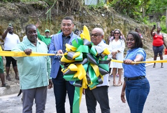 Prime Minister, Dr. the Most Hon. Andrew Holness (second left), cuts the ceremonial ribbon to mark the completion of the Hills of Spicy Grove Infrastructure Project in Oracabessa, St. Mary, on April 24. He is joined (from left) by Minister without Portfolio in the Ministry of Economic Growth and Infrastructure Development with Responsibility for Land Titling and Settlements, and Member of Parliament for St. Mary Western, Hon. Robert Montague; Custos Rotulorum for St. Mary, Hon. Errol Johnson; and Permanent Secretary in the Ministry, Arlene Williams. 
