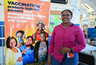 Community Peer Educator at the St. Thomas Health Department, Naqwayne McFarlane, stands beside a poster highlighting Vaccination Week in the Americas at the Morant Bay Health Centre on April 30.