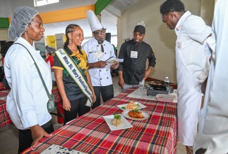 Miss St. Mary Festival Queen 2025, Anya Graham (second left), is given an overview by Annotto Bay High School student Adrian East of dishes on display at the Jamaica Cultural Development Commission (JCDC) Culinary Arts Competition and Showcase held in Port Maria, St. Mary, on May 21. Sharing in the moment are adjudicators (from left) Jaseth Jackson, Christopher Brown and Kenard Swaby.
