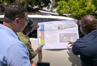 Prime Minister, Dr. the Most Hon. Andrew Holness (left) and Minister of Local Government and Community Development, the Hon. Desmond McKenzie (centre) view a proposal with city engineer for the Kingston and St Andrew Municipal Corporation (KSAMC), Zacia Chevannes during a tour of West Kingston on May 29. The Government of Jamaica in partnership with the KSAMC are working on plans geared towards creating new housing solutions in Denham Town, Kingston. 