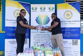 Kimberlee Solomon (left), Director of Corporate Planning and Client Relations at the Firearm Licensing Authority (FLA), presents items to Nellisa Asphall, Assistant Manager of the Maxfield Park Children’s Home, on Labour Day, May 25. The presentation and the repainting of the home