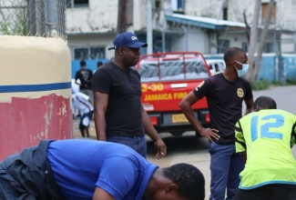 Members of the Jamaica Fire Brigade (JFB) repair a section of the sidewalk adjacent to the Stony Hill Fire Station in St. Andrew during the JFB