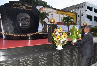 State Minister in the Ministry of Local Government and Community Development, Hon. Delroy Williams, representing Portfolio Minister, Hon. Desmond McKenzie, lays a floral tribute at the Secret Gardens monument in downtown Kingston, during Sunday’s (May 3) Child Month candlelight vigil in memory of Jamaican children who have died violently or tragically.
