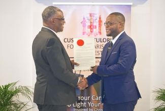 Custos Rotulorum for Manchester, Garfield Green (left), presents the instrument of office to Ricardo Smith, at the commissioning ceremony for 27 new Justices of the Peace (JPs) for Manchester, at The Garden Hotel in the parish on Thursday (April 30).