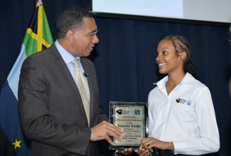 Prime Minister, Dr. the Most Hon. Andrew Holness (left), presents a plaque to Jamaica National Service Corps (JNSC) participant, Valesha Burke, for being the top student in the administrative assistant course under the JNSC Skills Track for Workforce Development. Occasion was the closing out ceremony for the first cohort of trainees under the programme at the Jamaica Defence Force (JDF) headquarters, Up Park Camp in Kingston on June 20, 2025.

