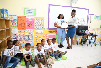 Literacy Coordinator for Barking Lodge Primary and Infant School, Mishkah Howard (left), presents a certificate of participation to Shantel Thomas of the Cheswick Branch Library, during Read Across Jamaica Day on May 5.