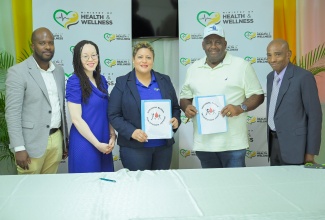 Minister of State in the Ministry of Health and Wellness, Hon. Krystal Lee (third left), and Chief Executive Officer of Skymar Building Construction and Maintenance Limited, Leon Grant (fourth left), display a contract valued $15 million for a major refurbishment of the National Chest Hospital Blood Collection Centre in St. Andrew, during a signing ceremony held at the institution on May 8. Others pictured (from left) are Civil Engineer with the Ministry, Desmond Hines; Director of the National Blood Transfusion Service (NBTS), Kamille West-Mitchell, and Chief Executive Officer of the Hospital, Barrington Graham.
