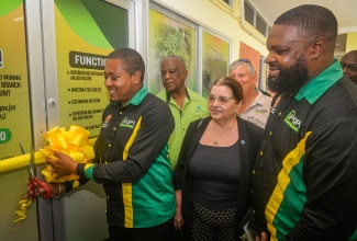 Minister of Agriculture, Fisheries and Mining, Hon. Floyd Green (left), cuts the ribbon to officially open the Seed and Nursery Certification Unit at the Bodles Research Station in St. Catherine on Friday (May 1). Looking on (from left) are: Minister of State in the Ministry, Hon. Franklyn Witter;  Food and Agriculture Organization of the United Nations (FAO) Representative for Jamaica, The Bahamas and Belize, Dr. Ana Touza; and Chief Plant Quarantine/Produce Inspector at the facility, Damian Rowe.