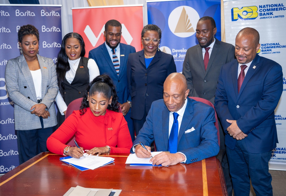 Development Bank of Jamaica (DBJ) Managing Director, Dr. David Lowe (right, seated), and Victoria Mutual (VM) Assistant Vice President – Lending Solutions and Business Services, Latoya Williams (left, seated), sign the Approved Financial Institutions (AFIs) agreement. Looking on are executives from DBJ and VM. The signing took place during the M5 Business Recovery Programme Additional Partner Commitment Ceremony, held on Wednesday (June 24) at the DBJ’s offices on Oxford Road in Kingston.
