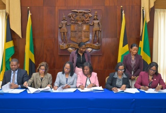 Director General, Office of Disaster Preparedness and Emergency Management (ODPEM), Commander Alvin Gayle (seated left), and Permanent Secretaries affix their signatures to a Memorandum of Understanding (MOU) for the GeoConnect Multi-Entry Data Governance Framework, at Jamaica House on Tuesday (June 2). The Permanent Secretaries are (from second left) Ministry of Industry, Investment and Commerce, Sancia Bennett-Templer; Ministry of Local Government and Community Development, Marsha Henry-Martin; Ministry of Economic Growth and Infrastructure Development, Arlene Williams; Ministry of Labour and Social Security, Dione Jennings (Acting); and Ministry of Tourism, Jennifer Griffith. Observing the signing are (from left) Acting Principal Director for Housing Management in the Ministry of Economic Growth and Infrastructure Development, Christina Gardner; and Principal Director of the National Spatial Data Management Branch in the Ministry, Alicia Edwards.
