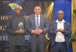 Prime Minister, Dr. the Most. Hon. Andrew Holness (centre), shares a photo opportunity with National Solid Waste Management Authority (NSWMA) employees (from left) Michael Williams and L. Francis, during the NSWMA Long-Service Awards Ceremony, held at AC Hotel in Kingston on Thursday (June 4).
