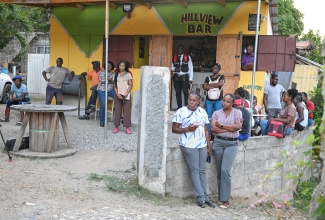 Corporal Junlie East of the Jamaica Constabulary Force (JCF) Community Safety and Security Unit (left, foreground), and Social Development Commission (SDC) Community Liaison Officer, Darlene McCalla, participate in a community meeting at Hill View Bar in Mt. Sinai, Llandewey, St. Thomas, on Wednesday (June 3). The meeting formed part of a JCF community walk-through aimed at sensitising residents on legal and community safety matters. 
