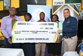 Minister of State in the Ministry of Labour and Social Security, Hon. Donovan Williams (right), and Supervisor at Gebbers Farms in the United States, Eyon Gayle (left), present a symbolic cheque valued $600,000, representing grants awarded to agricultural students in high schools across St. Mary. The presentation took place on June 5 at Wycliffe Martin High School. Receiving the cheque are Asheika Collingwood (second left) and Dontae Davis (centre) of St. Mary Technical High, joined by Wycliffe Martin High School Principal, Evorine Henry-Tracey.

