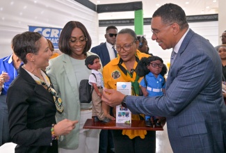 Prime Minister, Dr. the Most Hon. Andrew Holness; Speaker of the House of Representatives and wife of the Prime Minister, the Most Hon. Juliet Holness (second left); and Minister of Foreign Affairs and Foreign Trade, Senator the Hon. Kamina Johnson Smith (left), examine dolls created by Island Dolls Plus Collection, showcased by President of the organisation, Beverly Robotham-Reynalds. The occasion was a tour by the Prime Minister of booths in the marketplace area of the 11th Biennial Jamaica Diaspora Conference at the Montego Bay Convention Centre in St. James on Tuesday (June 16).
