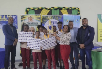 State Minister in the Ministry of Finance and the Public Service, and Member of Parliament for St. Ann South Western, Hon. Zavia Mayne (left), celebrates with the victorious Bethany Primary School team as they hoist the St. Ann South Western Quiz Competition championship trophy, successfully defending their title during the grand finale at Bethany Baptist Church. Joining them is Universal Service Fund (USF) Chief Executive Officer, Charlton McFarlane (right).
