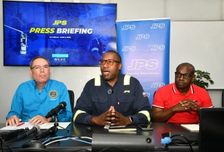 Minister of Energy, Transport and Telecommunications, Hon. Daryl Vaz (left), listens keenly as Jamaica Public Service (JPS) President and Chief Executive Officer (CEO), Hugh Grant (centre), responds to a question, during a press conference at the JPS Corporate Office in Kingston on Saturday (June 6). Also pictured is Director-General at the Office of Utilities Regulation (OUR), Ansord Hewitt.