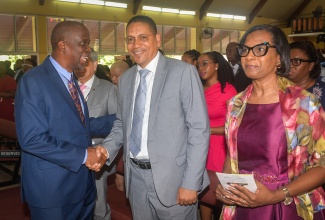 State Minister in the Ministry of Labour and Social Security, Hon. Donovan Williams (centre), is greeted by Pastor of the Boulevard Baptist Church, Rev. Devon Dick (left), during a church service, held at the Church on May 31, to commemorate the 60th anniversary of the National Insurance Scheme (NIS). At right is Acting Permanent Secretary in the Ministry of Labour and Social Security, Dione Jennings.