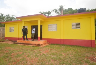 Resident of Dover in St. Catherine, Rohan Bullock (left), who is spearheading the community-led restoration of the Dover Community Centre, views the grounds of the facility. He is joined by community member, Stephan Williams.
