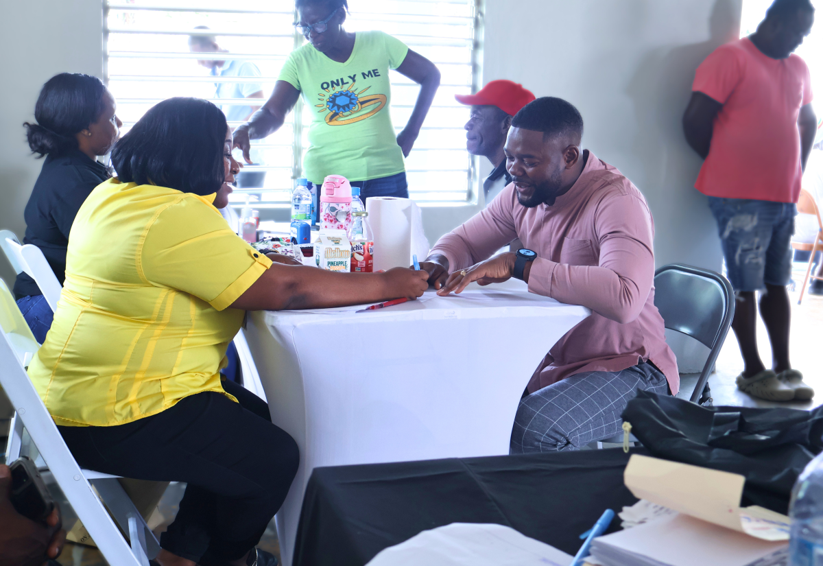 Mayor of Montego Bay, Councillor Richard Vernon, (right, seated), engages with Customer Service Manager at the Passport, Immigration and Citizenship Agency (PICA), Emoy Henry Tingling, during a job fair and document drive hosted at the Rose Heights Community Centre in St. James on June 4
