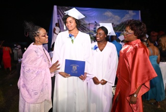 Permanent Secretary in the Ministry of Education, Skills, Youth and Information, Dr. Kasan Troupe (left), engages with Immaculate Conception High School graduates Shevanese Lopez (second left) and Khaydene Campbell, at the school
