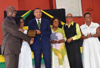 Prime Minister, Dr. the Most Hon. Andrew Holness (third left) makes a presentation to Pastor of the Olson Memorial Church of God, Reverend Adinhair Jones (left) and his wife, Pauline Jones (second left) at the National Emancipation and Independence Thanksgiving Church Service, held at the church on Hope Road, St. Andrew on Sunday (July 26). They are joined by (from third right) Minister of Culture, Gender, Entertainment and Sport, Hon. Olivia Grange; Minister of Finance and the Public Service, Hon. Fayval Williams; and Senator Kisha Anderson representing Leader of the Opposition, Mark Golding.