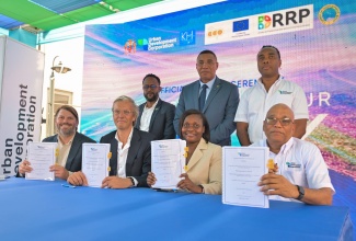 Prime Minister, Dr. the Most Hon. Andrew Holness (standing, centre), participates in the signing of the agreement for consultancy services for segment two of the Kingston Harbour Walk Project at the Carib Cement Sports Club and Wellness Centre in Rockfort, Kingston, on Wednesday (July 22). He is joined by Representative, Caribbean Development Bank (CDB), Dr. Oronde Small (standing, left) and Urban Development Corporation (UDC) General Manager, Robert Honeyghan (standing right). Displaying copies of the signed agreement (from left) are consultants Co-founder of Felixx Landscape Architects and Planners, Michiel Van Driessche, and founder of Cityförster, Martin Sobota;  Permanent Secretary in the Ministry of Economic Growth and Infrastructure Development, Arlene Williams; and (UDC) Chairman, Norman Brown. 
