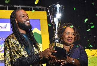  Minister of Culture, Gender, Entertainment and Sport, Hon. Olivia Grange (right) presents 2026 Jamaica Festival Song Competition winner, dBurnz with his trophy at the grand finals of the competition held on Saturday (July 25) at the Ranny Williams Entertainment Centre in St. Andrew. 
