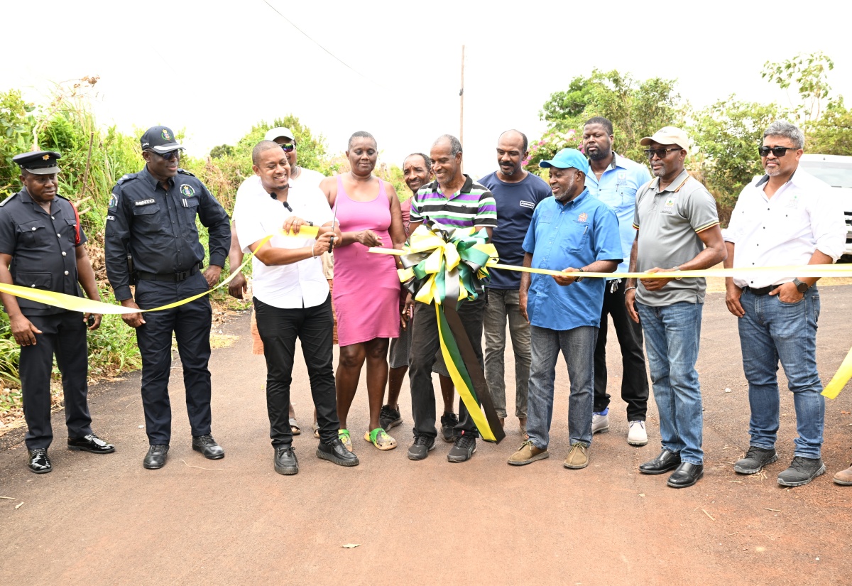Minister of Agriculture, Fisheries and Mining, Hon. Floyd Green (third left), joins farmer, Aslyn Amos Parchment (front, centre) in cutting the ribbon to officially open the newly rehabilitated Newcombe Valley to Amos Lane road in the Pedro Plains area of St. Elizabeth, on Wednesday, August 26. Looking on are Head of the St. Elizabeth Police Division, Superintendent Coleridge Minto (second left); Permanent Secretary, Ministry of Agriculture, Fisheries and Mining, Dermon Spence (third right); Chief Executive Officer of the Rural Agricultural Development Authority (RADA), Garnet Edmondson (second right; Parish Manager of Rural Agricultural Development Authority (RADA), St. Elizabeth, Mark Lee (right); farmers and other stakeholders.
