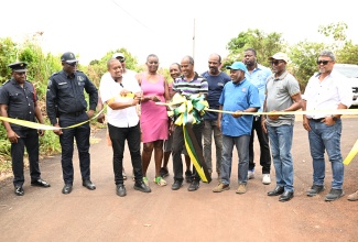 Minister of Agriculture, Fisheries and Mining, Hon. Floyd Green (third left), joins farmer, Aslyn Amos Parchment (front, centre) in cutting the ribbon to officially open the newly rehabilitated Newcombe Valley to Amos Lane road in the Pedro Plains area of St. Elizabeth, on Wednesday, August 26. Looking on are Head of the St. Elizabeth Police Division, Superintendent Coleridge Minto (second left); Permanent Secretary, Ministry of Agriculture, Fisheries and Mining, Dermon Spence (third right); Chief Executive Officer of the Rural Agricultural Development Authority (RADA), Garnet Edmondson (second right; Parish Manager of Rural Agricultural Development Authority (RADA), St. Elizabeth, Mark Lee (right); farmers and other stakeholders.
