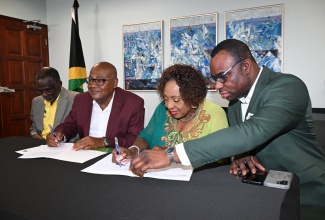 Minister of Culture, Gender, Entertainment and Sport, Hon. Olivia Grange, and Jamaica Football Federation (JFF) President, Michael Ricketts (second left), sign the Guarantee Agreement for Jamaica’s co-hosting of the 2031 FIFA Women’s World Cup at the Ministry’s offices in Kingston on Tuesday (August 11). Sharing in the occasion are Permanent Secretaries in the Ministry, Denzil Thorpe (left) and DeanRoy Bernard.

