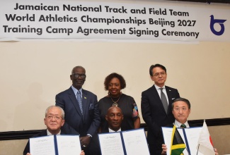 Minister of Culture, Gender, Entertainment and Sport, Hon. Olivia Grange (centre, back row), observes as President of the Japan-based Tottori Athletics Association,  Shinichi Hamasaki (left, seated); President of the Jamaica Athletics Administrative Association (JAAA), Garth Gayle (centre), and Governor of Tottori, Shinji Hirai (right), display the signed training camp agreement between the JAAA and Tottori Prefecture, Japan, during press conference at The Jamaica Pegasus hotel, in New Kingston, on August 31. Others pictured (from left, back row) are Minister of Local Government and Community Development, Hon. Desmond McKenzie, and Japan’s Ambassador to Jamaica, Kohei Maruyama.
