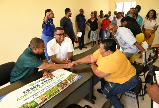 Minister of Agriculture, Fisheries and Mining, Hon. Floyd Green (left), greets farmer Nicolea Morgan (right), during the Essex Valley Agro-Economic Zone handover ceremony in St. Elizabeth on Wednesday (Sept. 2). Looking on is President of Essex Valley Farmers Benevolent Society, Imran Powell (centre).
