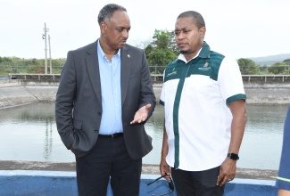 Minister of Agriculture, Fisheries and Mining, Hon. Floyd Green (right), listens to Managing Director, Jamaica Social Investment Fund, Omar Sweeney, following the official commissioning of the irrigation transmission at Ebony Park Agro Park in Clarendon, on Thursday (September 17).
