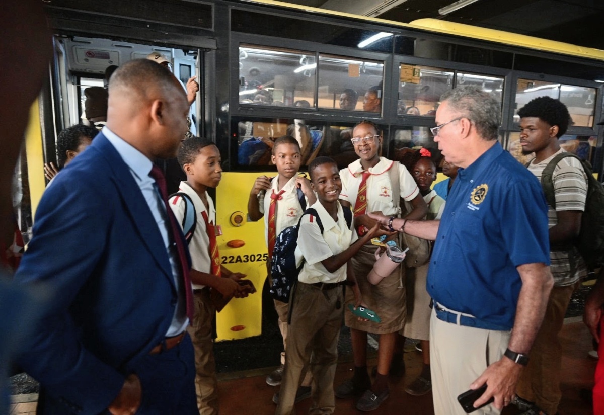 Minister of Energy, Transport and Telecommunication,  Hon Daryl Vaz (right), greets  students of Mona High School before they board a bus for school inside the Half-Way Tree Transportation Centre on Monday (September 7). Sharing in the moment was Managing Director, Transport Authority, Ralston Smith.
