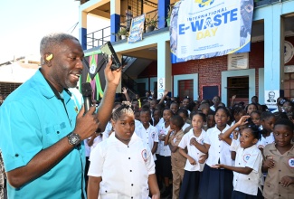 Chief Executive Officer of INET Jamaica Limited, Kirk-Lyle Hall (left) makes a presentation to students on e-waste disposal during the National Solid Waste Management Authority (NSWMA) International E-Waste Day observance at St Aloysius Primary School in Kingston on Wednesday (October 14).
